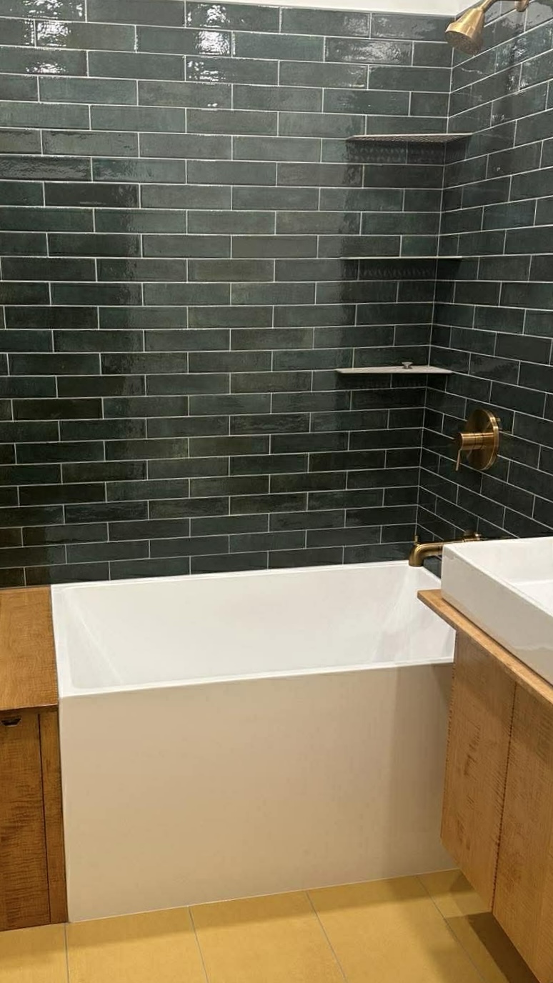 Dark green glazed tile shower with brass fixtures